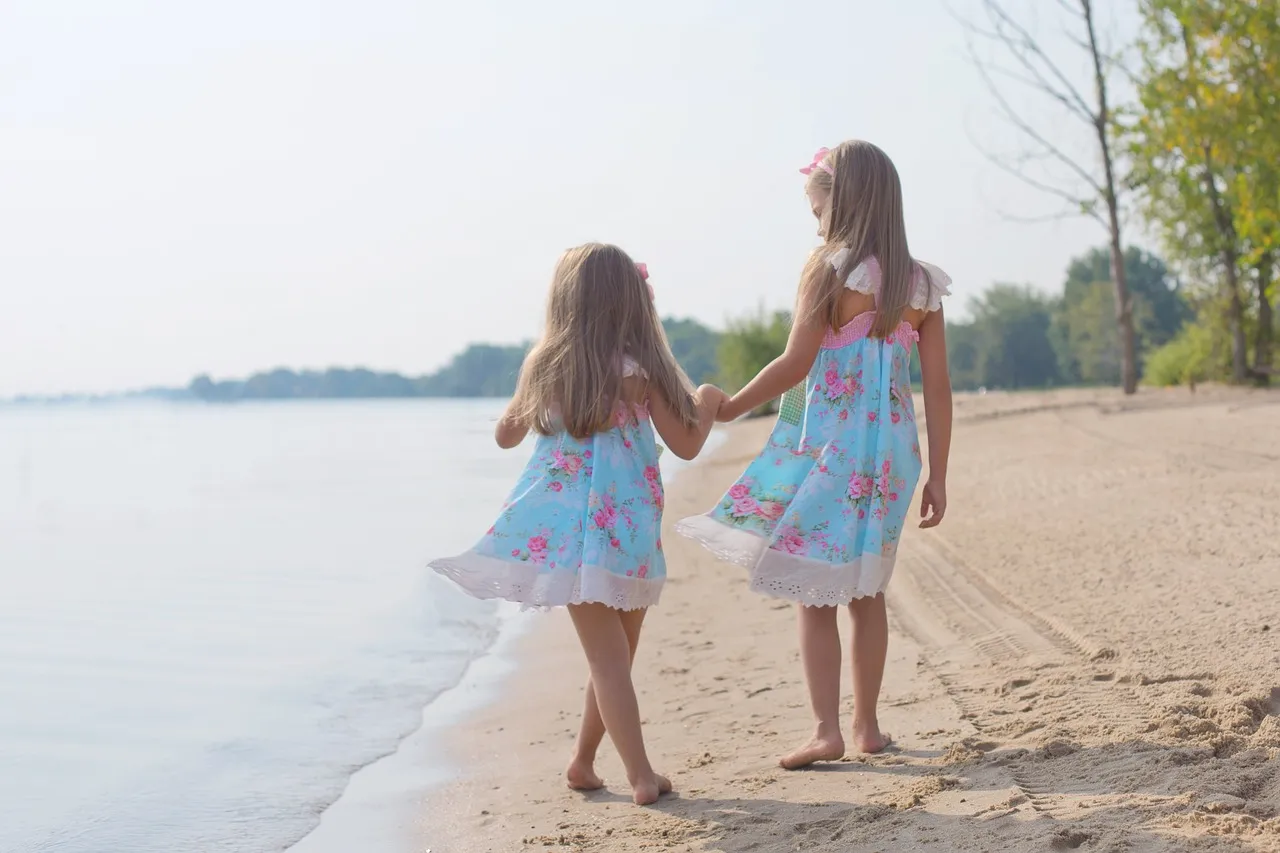 海辺で手を繋いでいる子供の姉妹